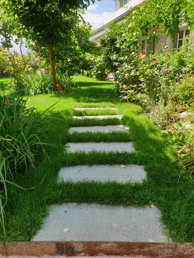 Chemin en pas japonais traversant une pelouse luxuriante dans un jardin paysager à Chens-sur-Léman en Haute-Savoie (74)