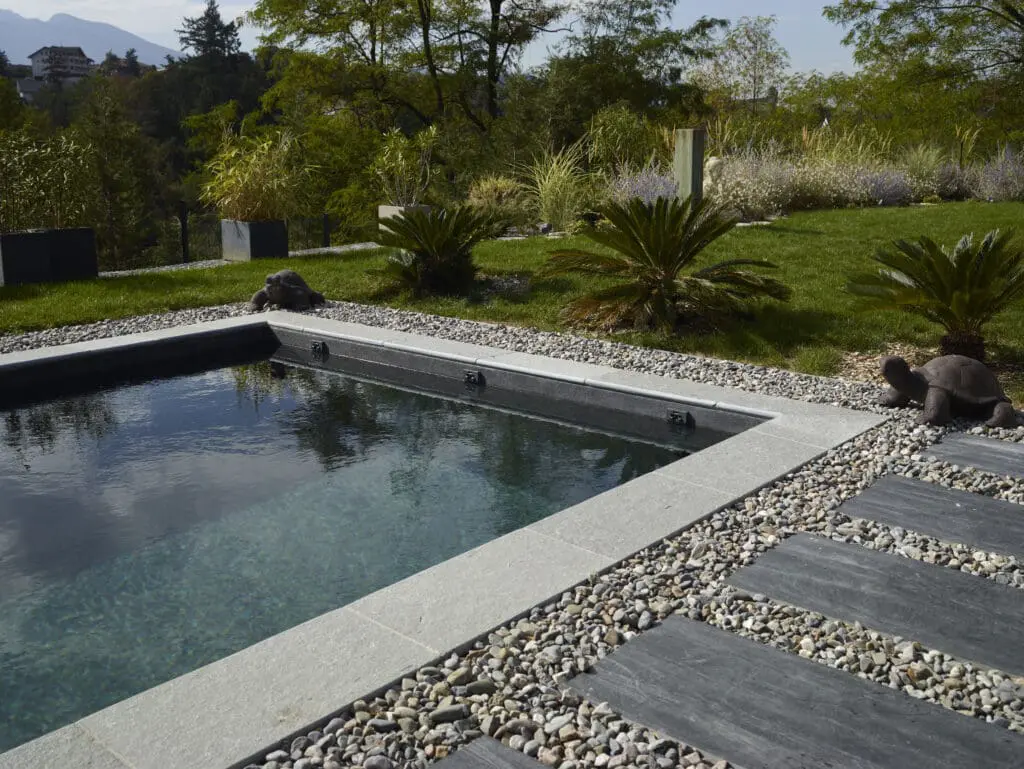 Piscine moderne avec margelles en pierre, graviers décoratifs et jardin paysager à Thonon-Les-Bains