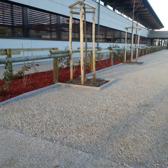 Cour d'école aménagée avec allée en graviers, jardinières et clôture en bois à Douvaine (74)