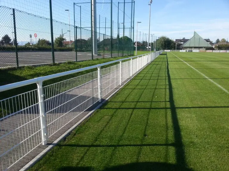 Clôture et pare-ballon autour d'un terrain de sport engazonné