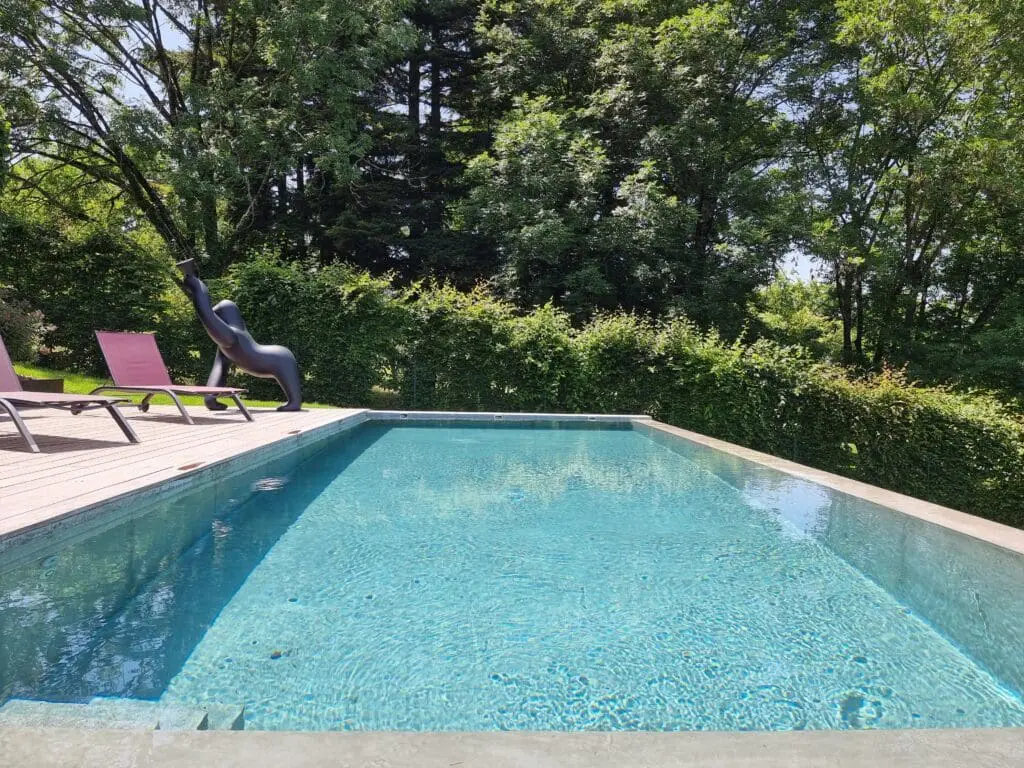 Piscine à débordement avec plage en bois exotique et vue dégagée sur le jardin à Thonon-les-Bains, réalisée par Pernollet Paysage