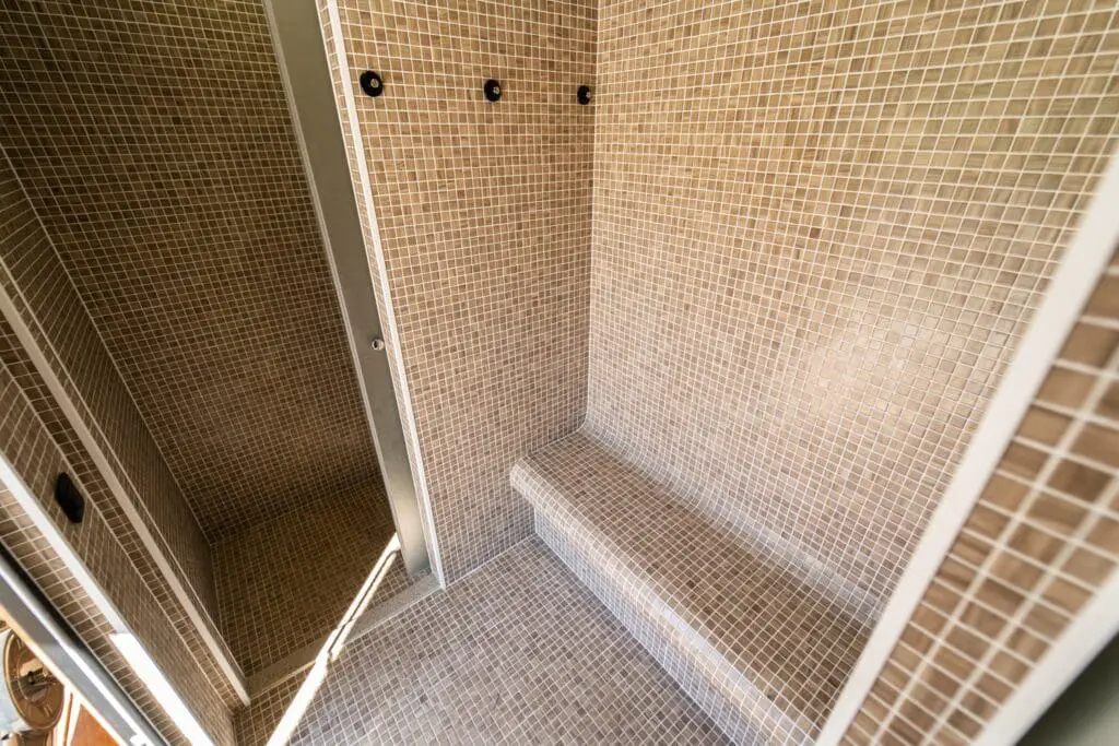 Intérieur d’un hammam en mosaïque avec banc intégré, conçu dans un espace wellness par Pernollet Paysage à Neuvecelle.