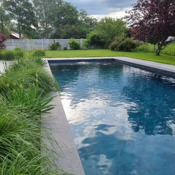 Piscine sur mesure à Armoy avec aménagement végétal en bordure, réalisée par Pernollet Paysage.