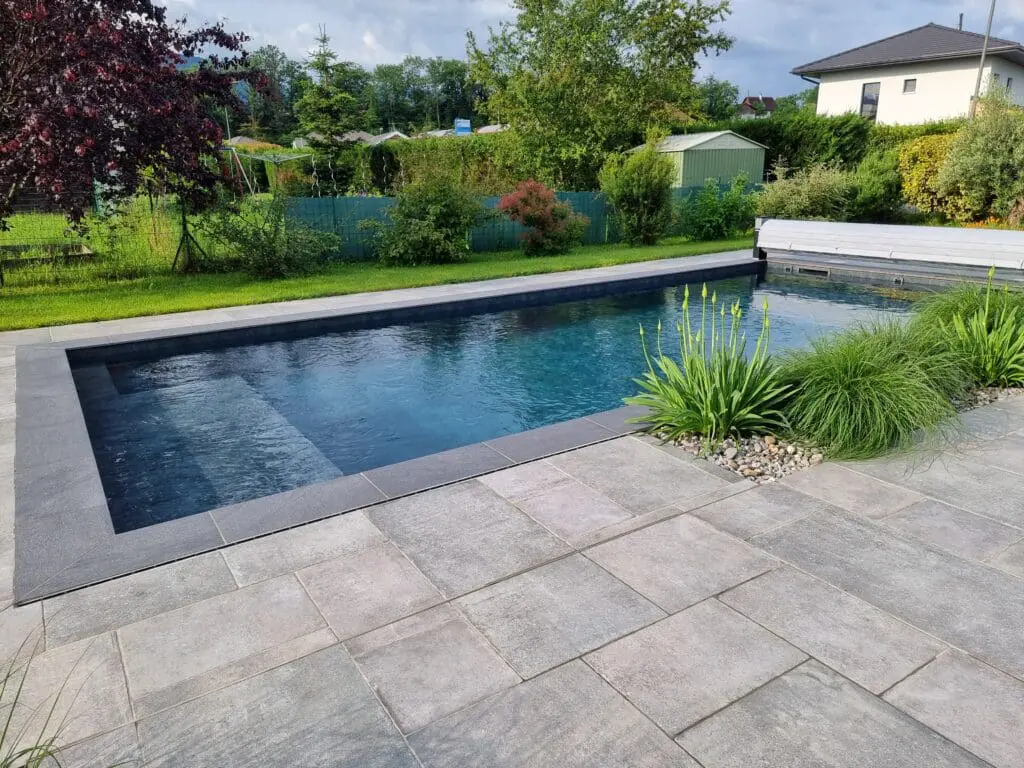 Piscine sur mesure à Armoy entourée d’un jardin paysager avec graminées et haie de bambous, réalisée par Pernollet Paysage.