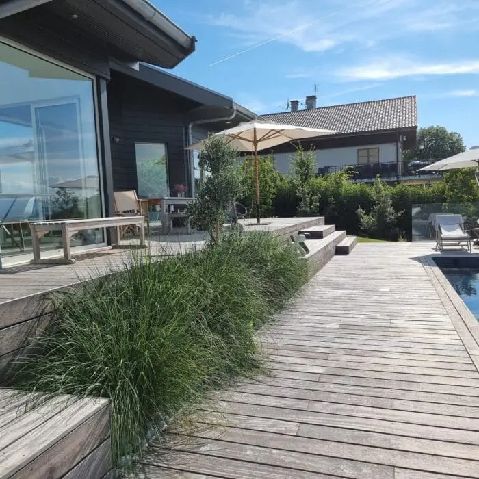 Piscine sur mesure en béton avec revêtement texturé et plage en bois, conçue par Pernollet Paysage à Neuvecelle.
