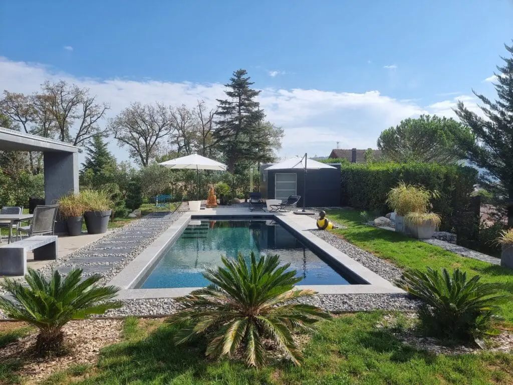 Piscine design à Thonon-les-Bains avec plage en pierre calcaire et jardin paysagé