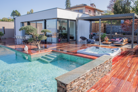Conception et réalisation des aménagements extérieurs d’une villa et d’une piscine en béton brut avec paroi de verre.