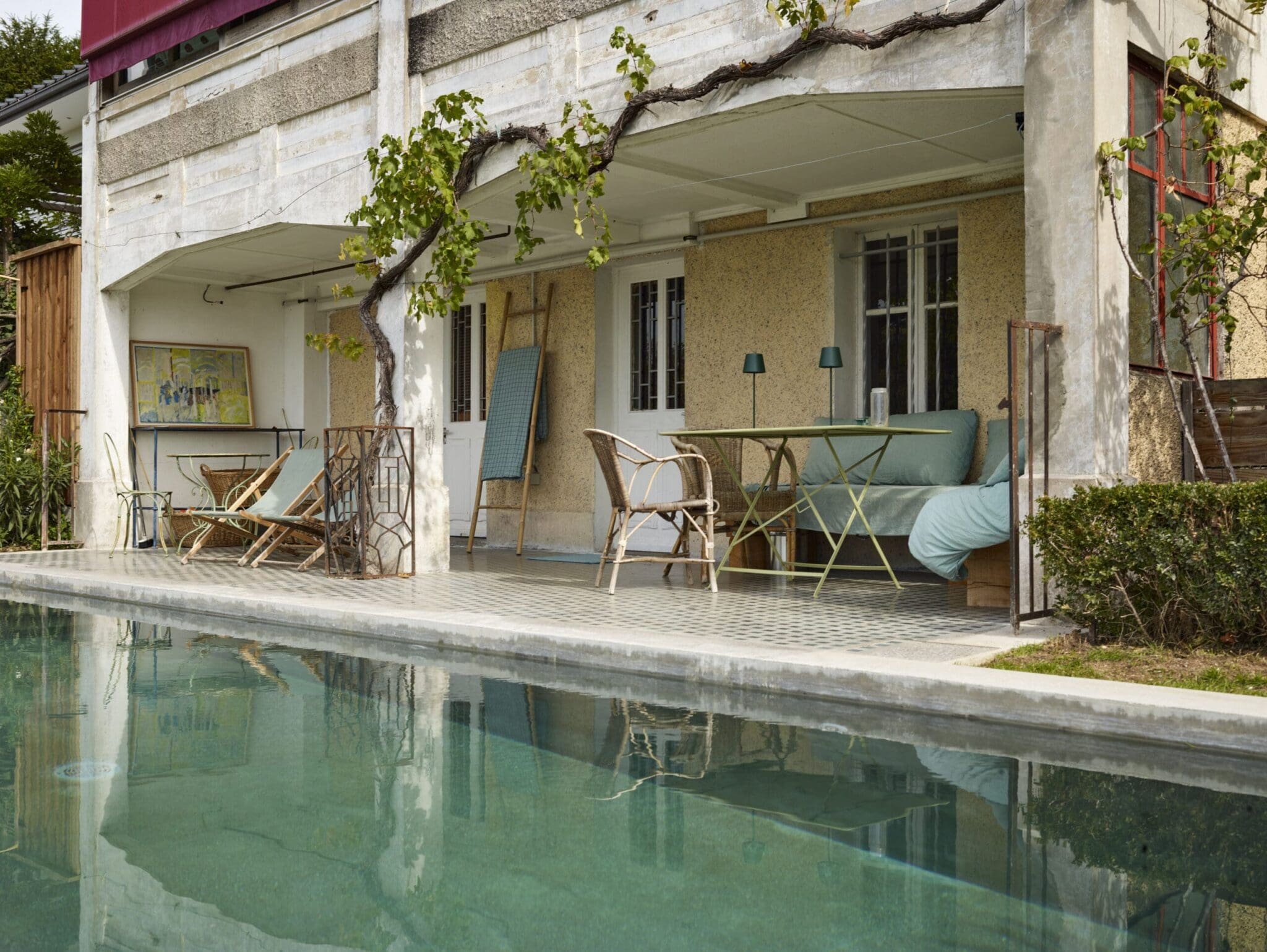 Piscine rectangulaire avec terrasse couverte, entourée d'un jardin luxuriant à Thonon-Les-Bains.