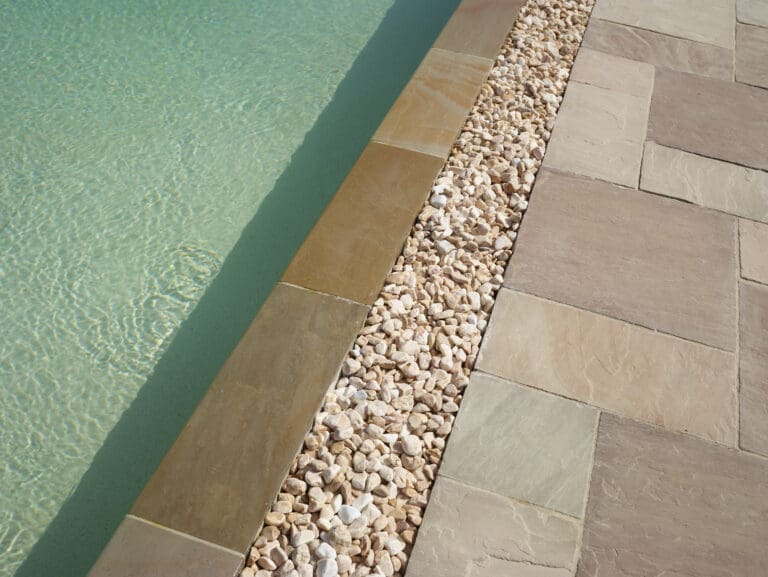 Détail d'une piscine miroir avec margelle en pierre naturelle et drainage en galets à Ballaison en Haute-Savoie (74)
